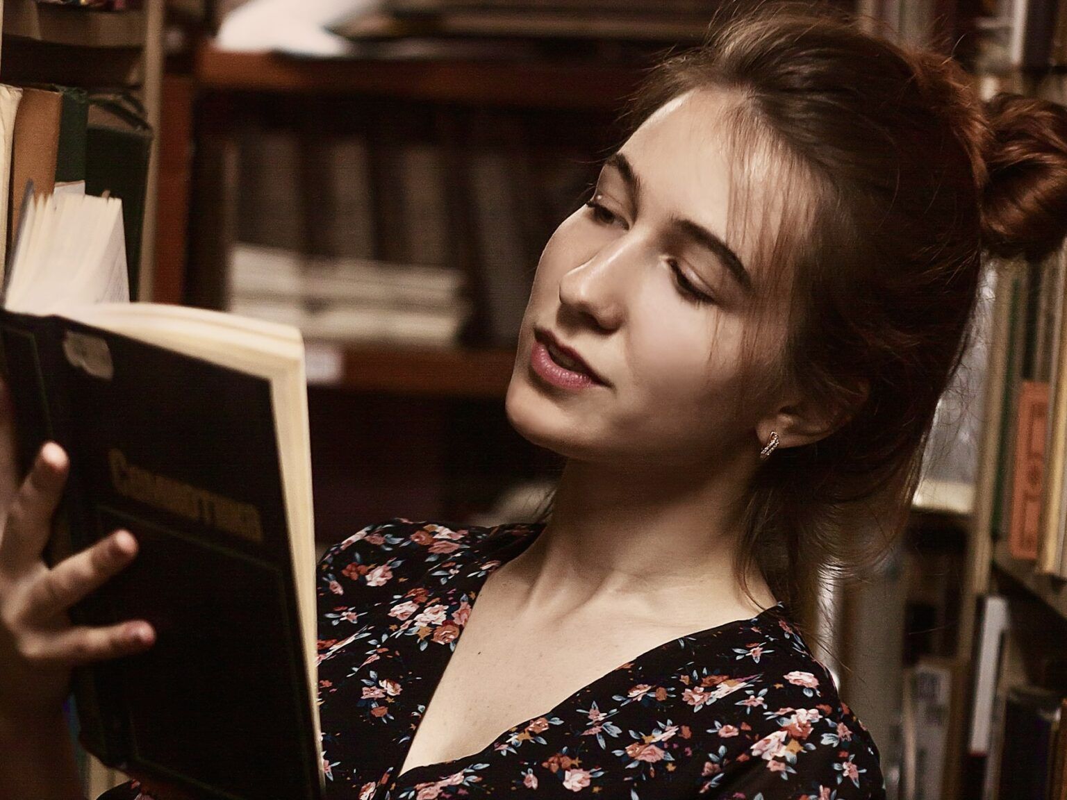 A young lady reading a book in a library